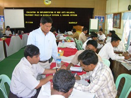 Leonard standing over a few colleagues seated at a table