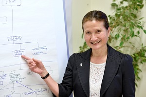 photo shows Rosanna pointing at a whiteboard
