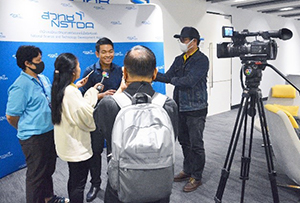 Image shows a press interview with camera