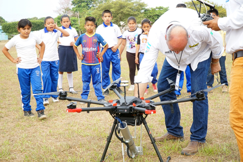 a man using a drone with children in background