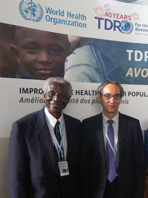 Image shows Professor Adetokunbo Lucas with a colleague standing in front of a TDR banner